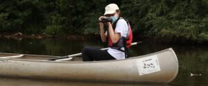 student on canoe taking video of the river